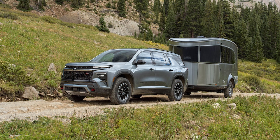 2024 Chevrolet Traverse towing a camper through a hillside road.