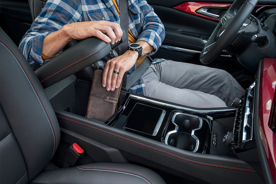 A person stowing a wallet in the Interior Centre Console Storage of the 2024 Chevrolet Traverse.