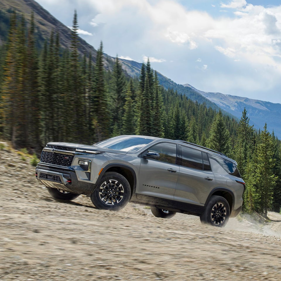 2024 Chevrolet Traverse driving uphill with mountains in the background.