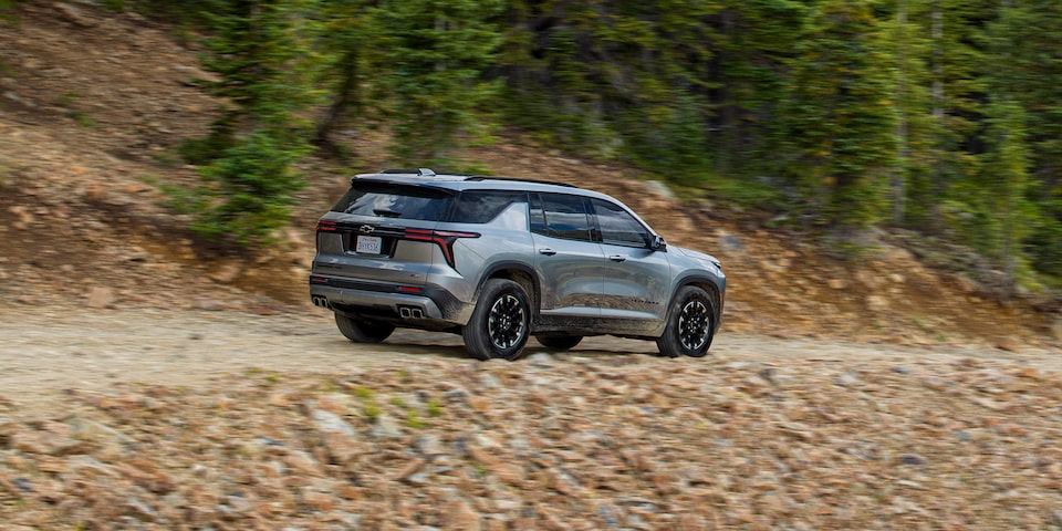 Side profile view of the 2024 Chevrolet Traverse driving on a gravel road.