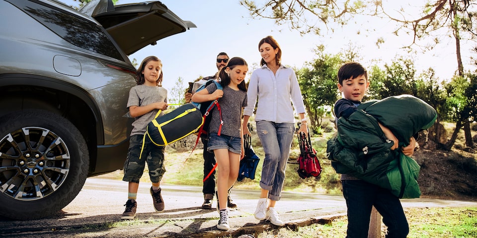 A family unloading their camping gear from the trunk of a 2024 Chevrolet Traverse.