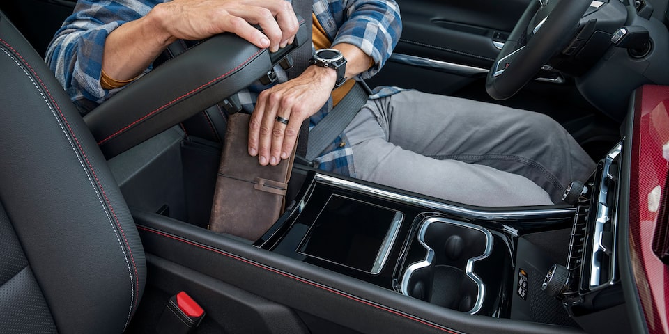 A person placing his wallet on the Interior Centre Console Storage of the 2024 Chevrolet Traverse.