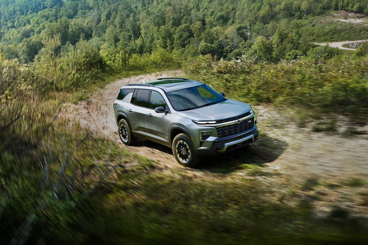 2024 Chevrolet Traverse driving off-road on a tree-lined road.