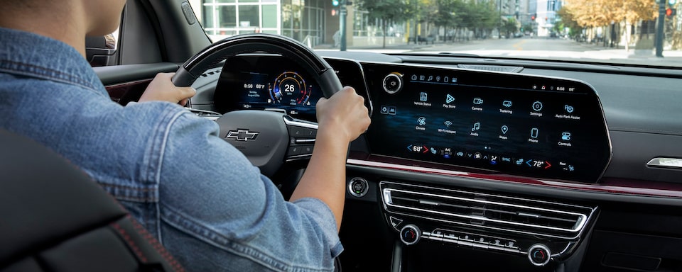 A person driving the 2024 Chevrolet Traverse while utilizing the Infotainment System Display.