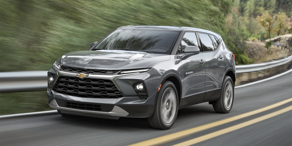 Vue latérale avant du Chevrolet Blazer 2025 en mouvement sur une route de campagne.