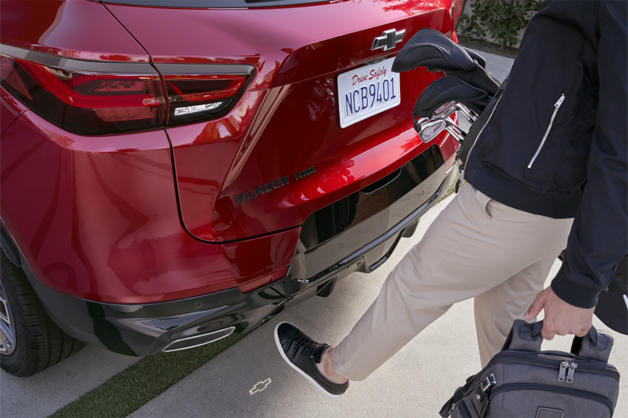 Une personne approche du coffre du Chevrolet Blazer 2025 avec des objets dans les mains.