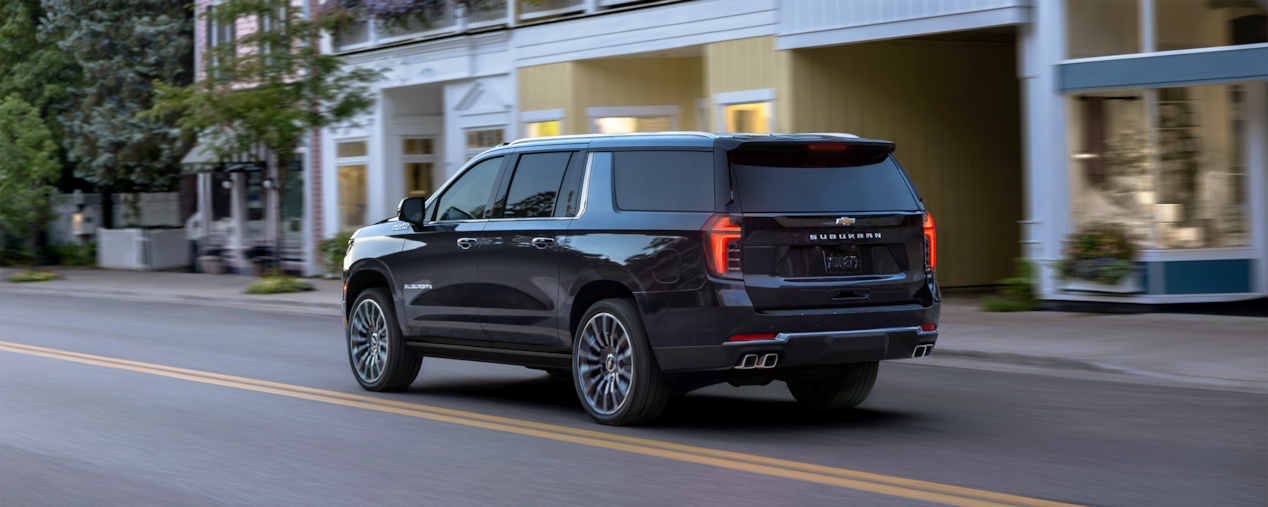 Back-side view of the 2025 Chevrolet Suburban SUV driving in the city.