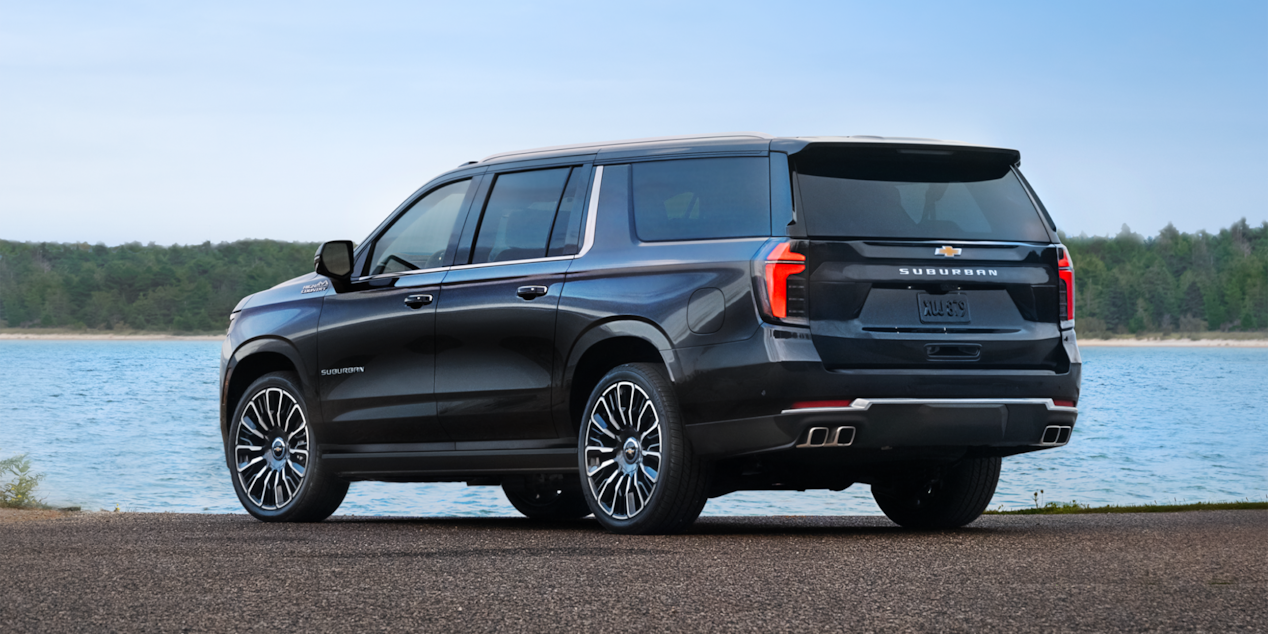 Back-side view of the 2025 Chevrolet Suburban SUV parked by the lake.