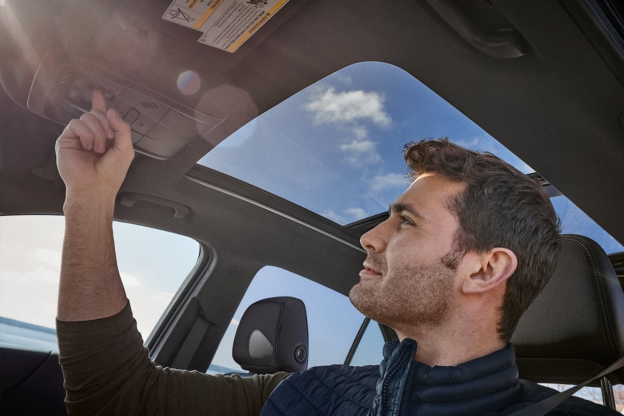 A man opens the sunroof of his 2024 Chevrolet Equinox.