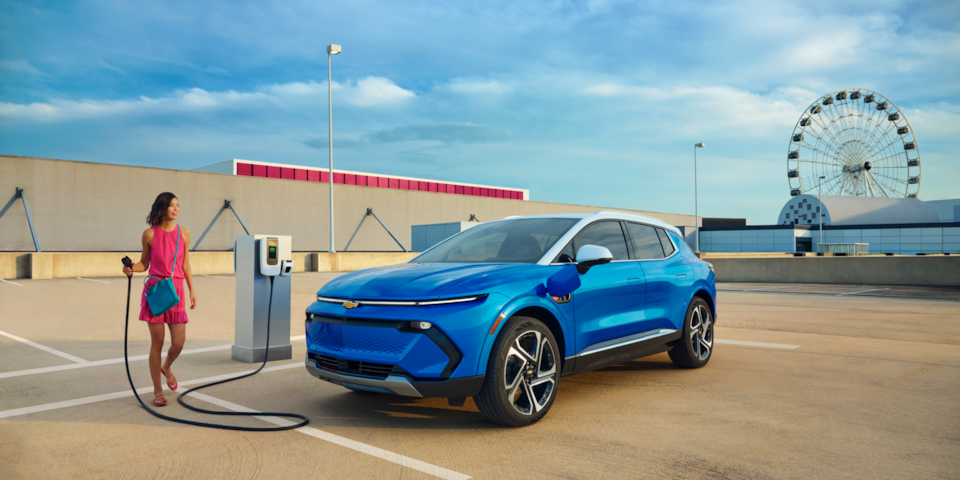 A woman charging a Chevrolet Blazer EV at a public charging station.