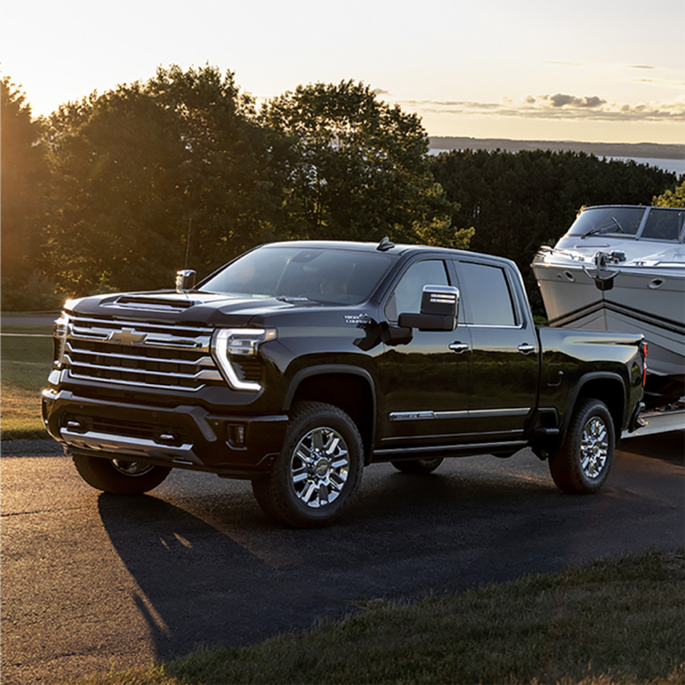 2025 Chevrolet Silverado HD pickup truck towing a trailer while driving.