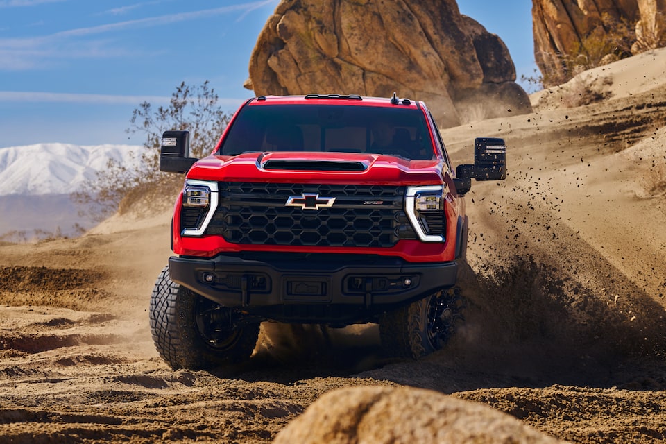 Camion ZR2 rouge qui soulève du sable dans le désert.