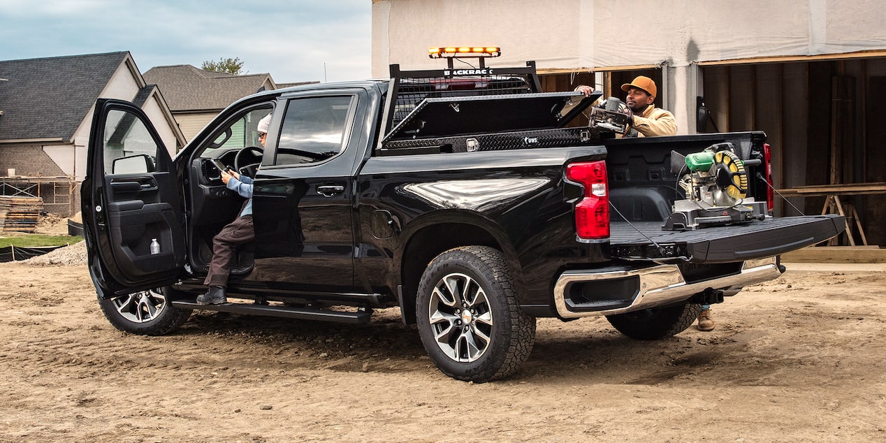 Construction workers getting equipment from the cargo bed of the 2024 Chevrolet Silverado work truck.