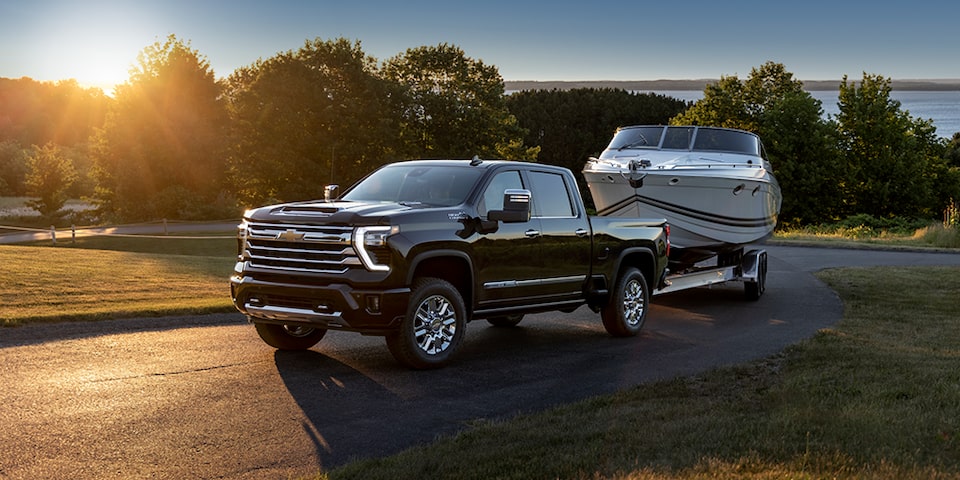 A Chevrolet Pickup Truck towing a speedboat on the road.