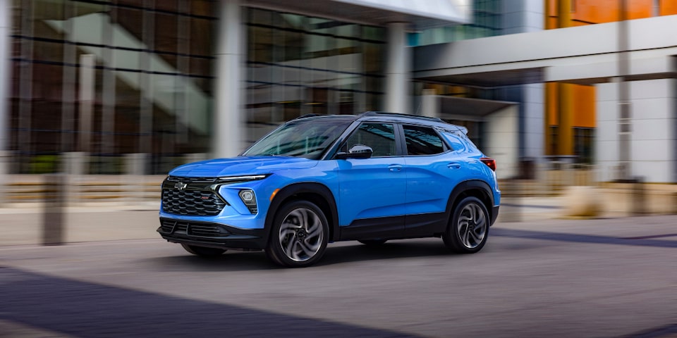 The 2024 Chevrolet Trailblazer driving past a modern building.