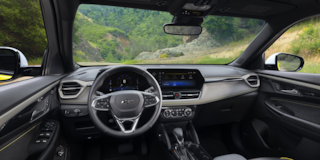 Rear passenger's view of the interiors of the 2024 Chevrolet Trailblazer parked on a hillside road.