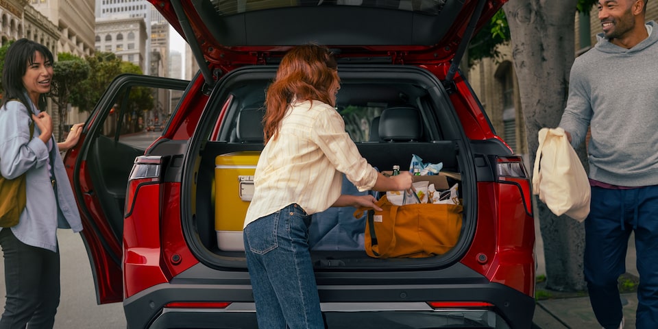 People unloading belongings in the spacious rear cargo space of the 2025 Chevrolet Equinox compact SUV.