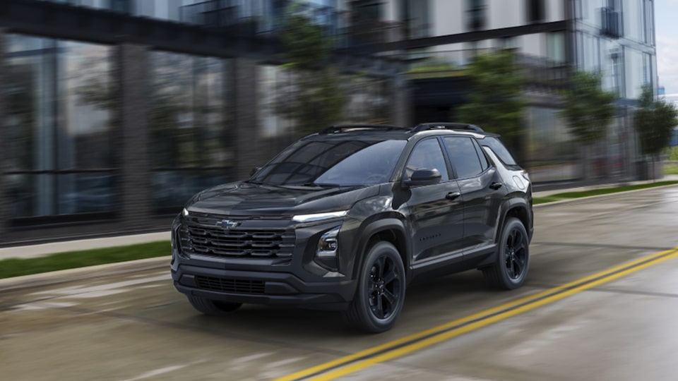 2025 Chevrolet Equinox compact SUV Midnight edition driving alone on a city street.