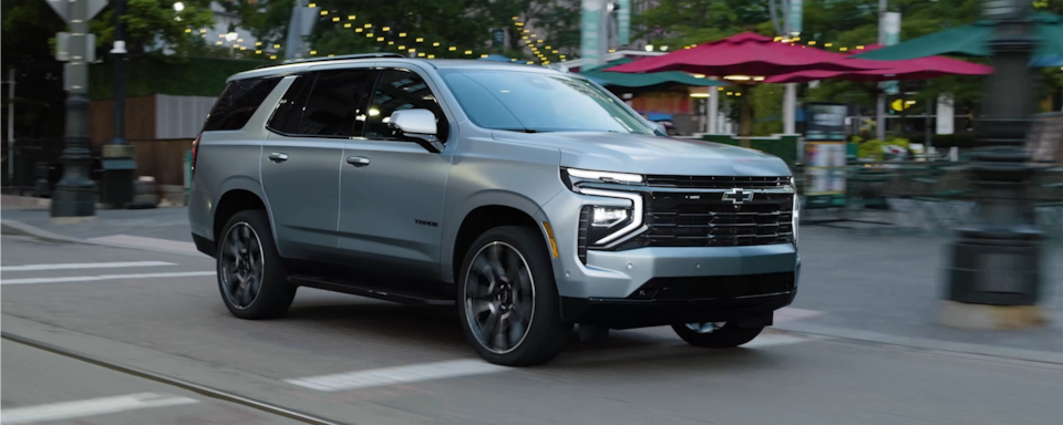 Vue latérale avant du VUS Chevrolet Tahoe 2025 en mouvement en ville.