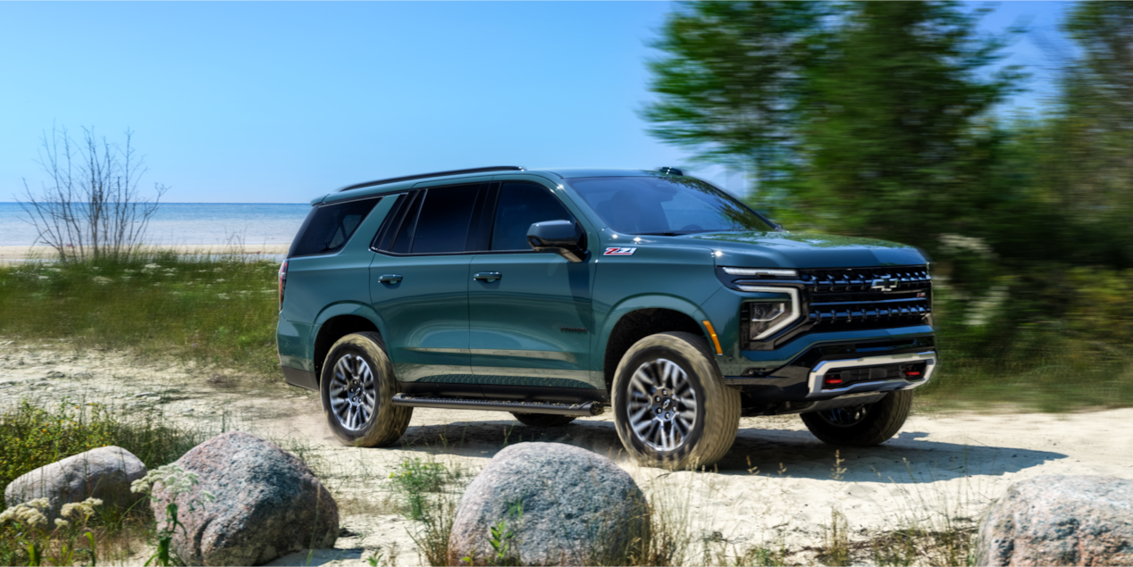 Vue latérale avant du VUS Chevrolet Tahoe 2025 stationné près d’une plage.