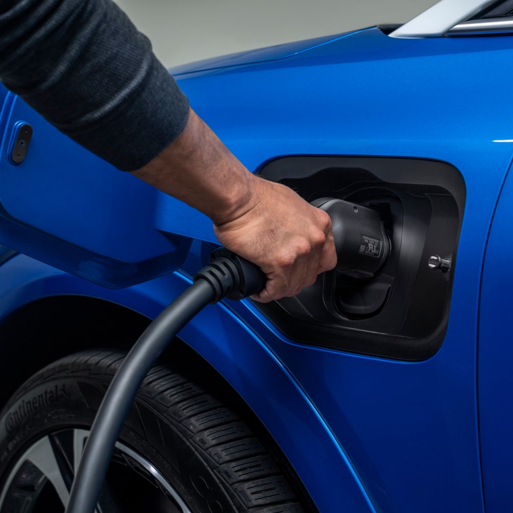 A 2025 Chevrolet Equinox EV getting charged by a person.