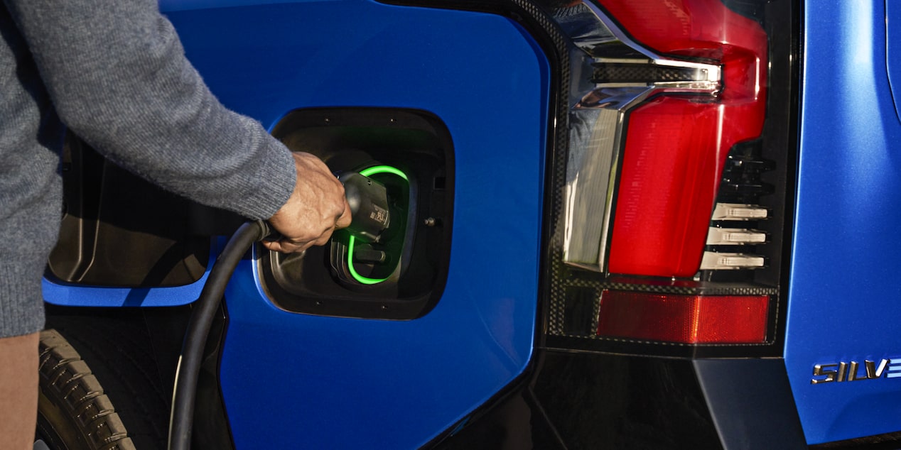 A person plugging in a charger to a 2025 Chevrolet Silverado EV.