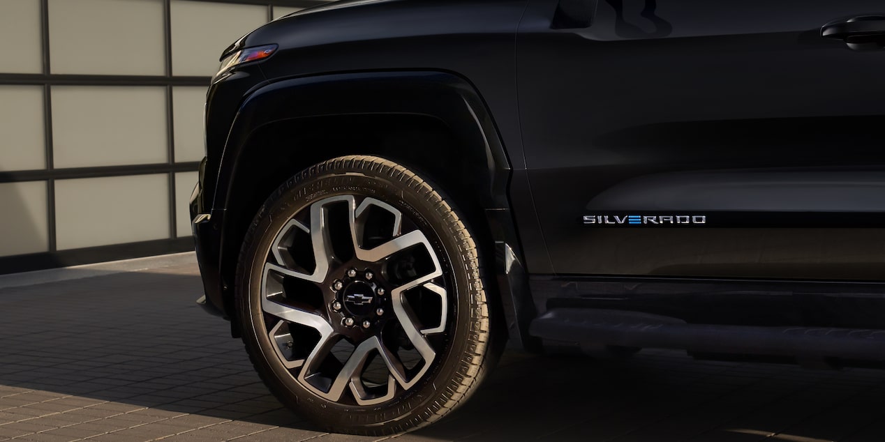 Close-view of the sides of a 2025 Chevrolet Silverado EV parked in front of a garage.