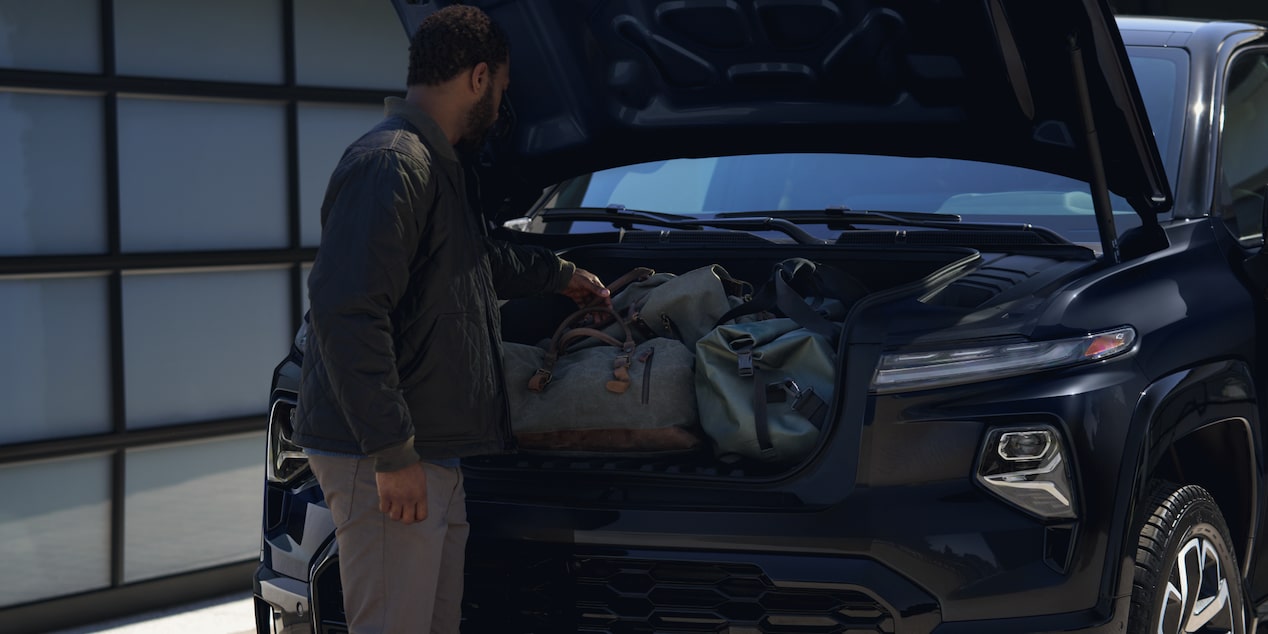 A person stowing some belonging in the trunk of a 2025 Chevrolet Silverado EV.