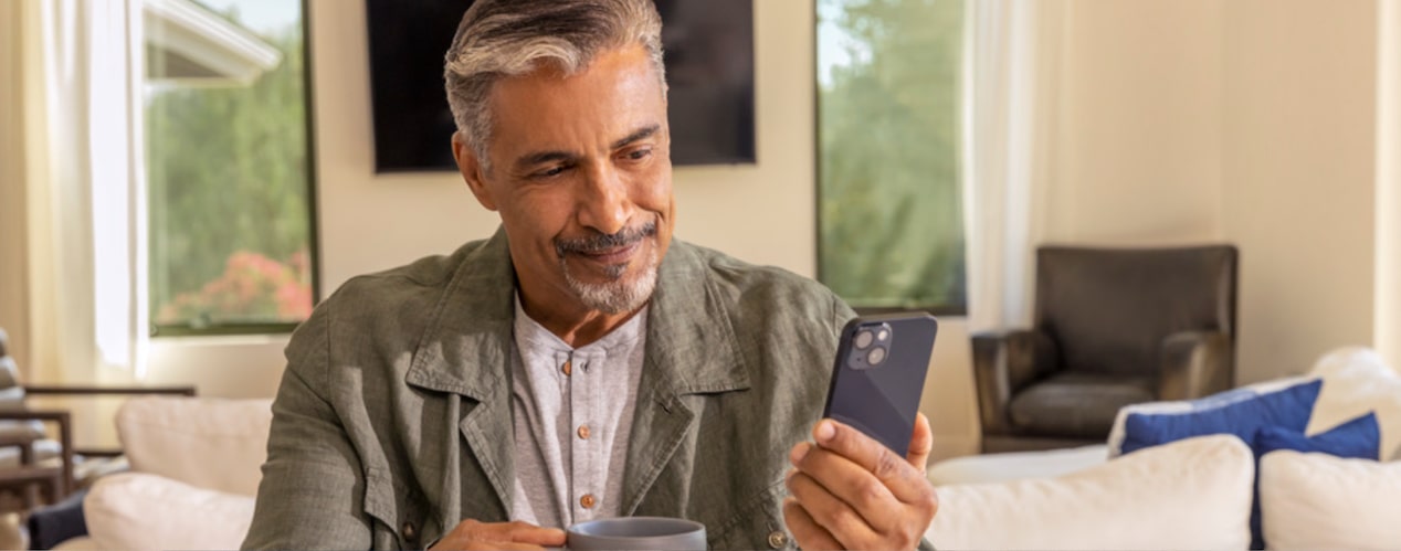 Smiling Man Holding Mobile Phone in Living Room