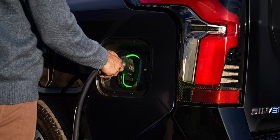 Une personne branchant son Chevrolet Silverado EV avec un chargeur domestique.