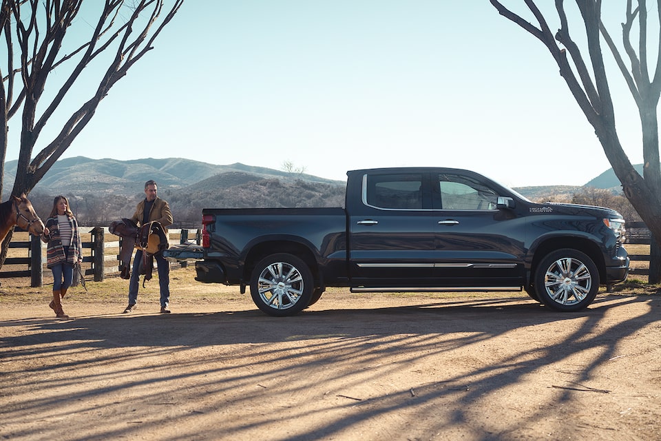 Two people loading their horse equipment on the 2024 Chevrolet Silverado High Country model.