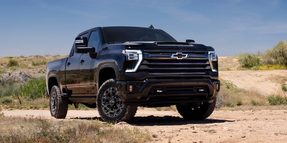 2025 Chevrolet Silverado High Country Midnight HD pickup truck parked on a hill.