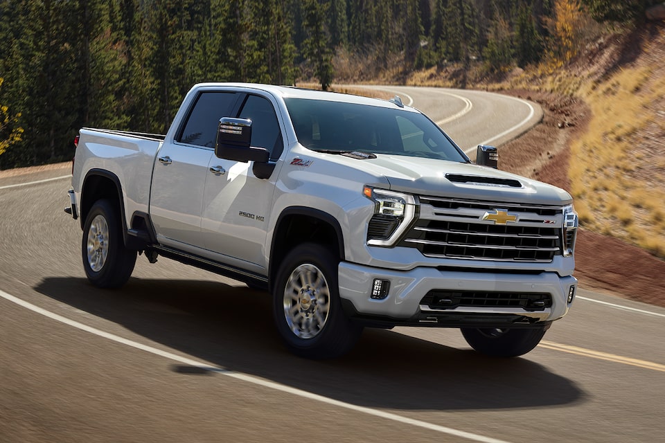 2025 Chevrolet Silverado Z71 Chrome Sport HD pickup truck driving on a countryside road.