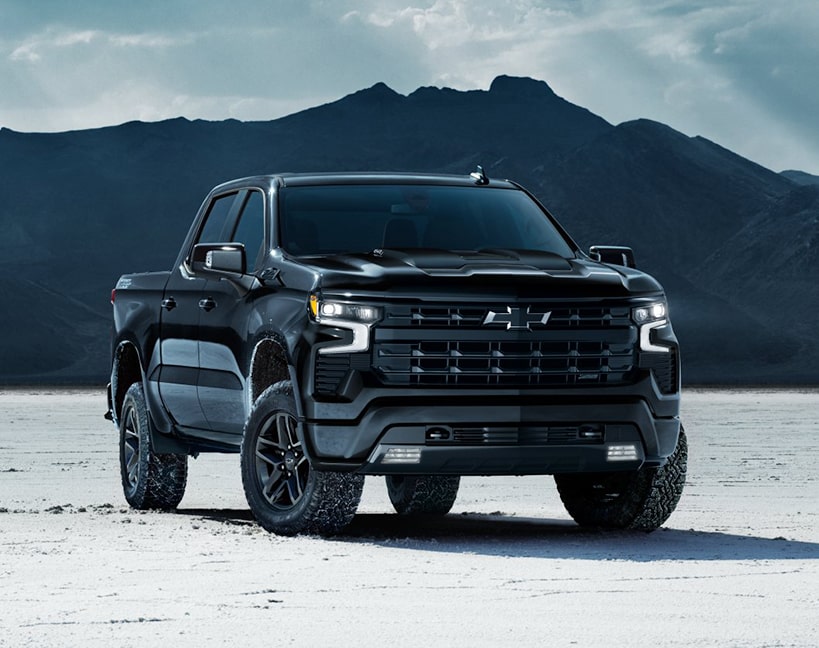 The 2025 Chevrolet Silverado LD parked near the mountains on a snow- covered ground.