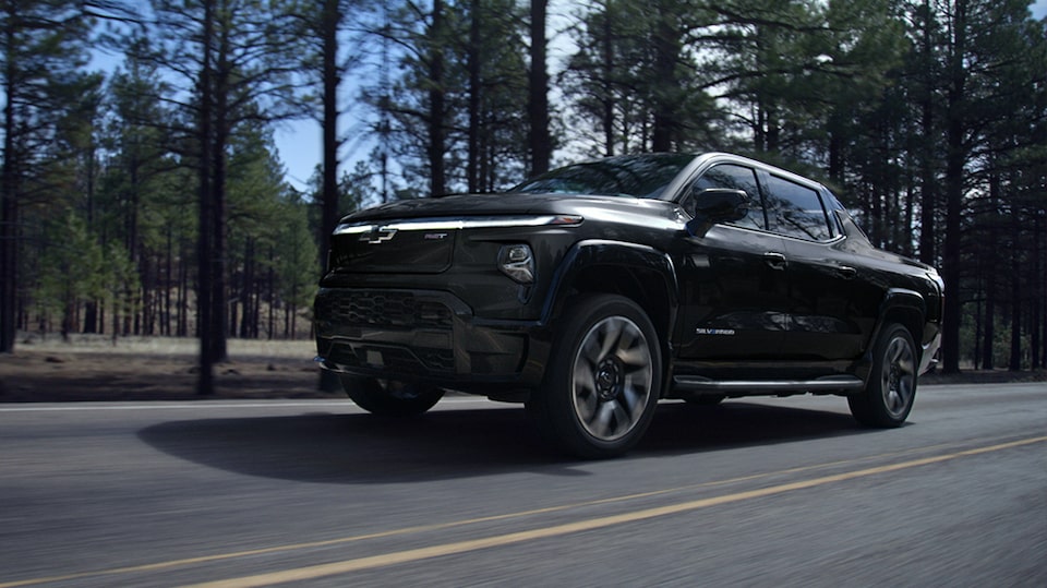 2024 Chevrolet Silverado EV driving down a road on an arid environment.