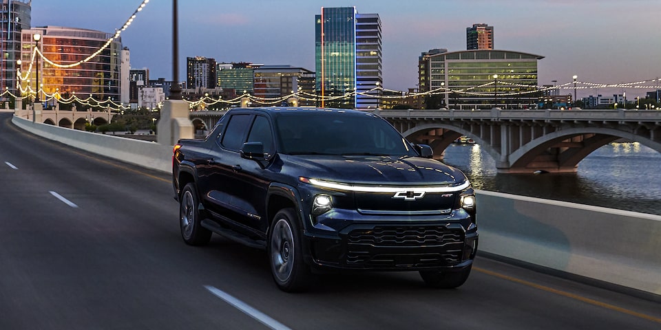 2024 Chevrolet Silverado EV driving during dusk on a city bridge.