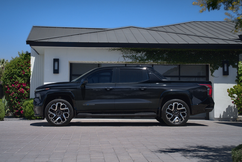 Side-profile view of the 2024 Chevrolet Silverado EV parked outside a house.