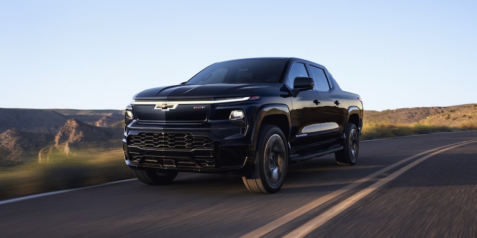 The 2024 Chevrolet Silverado EV cruising along a scenic road with mountains.