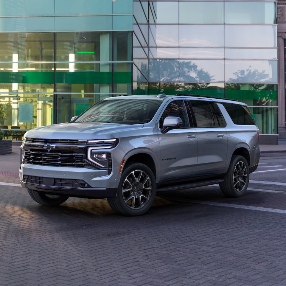 Front Three-Quarters View of the 2025 Chevrolet Suburban SUV Parked in Front of a Business