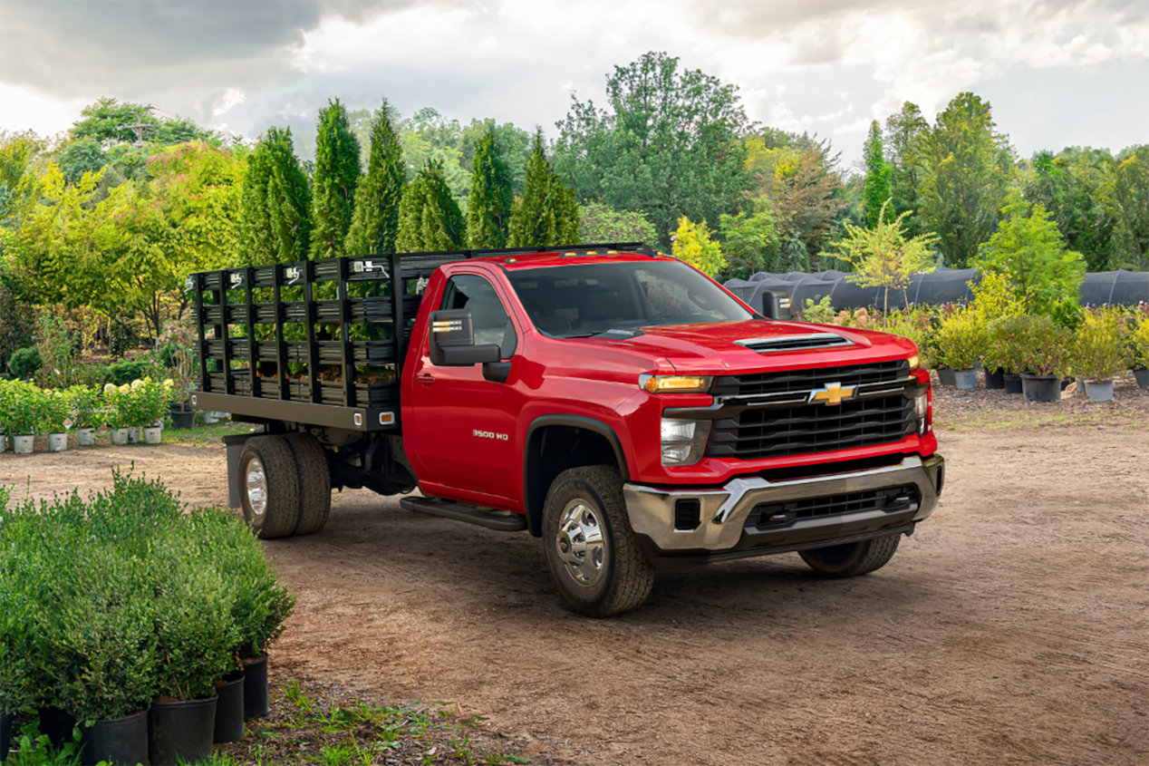 2024 Chevrolet Silverado 3500 HD Chassis Cab with a utility trailer in a rural construction site.