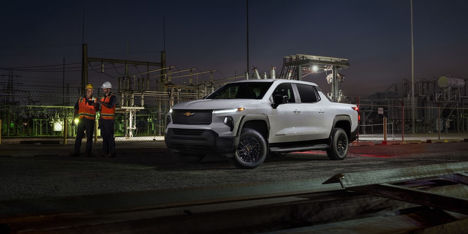 Front-side view of a 2025 Chevrolet Silverado EV Work Truck stationed by the road at night.