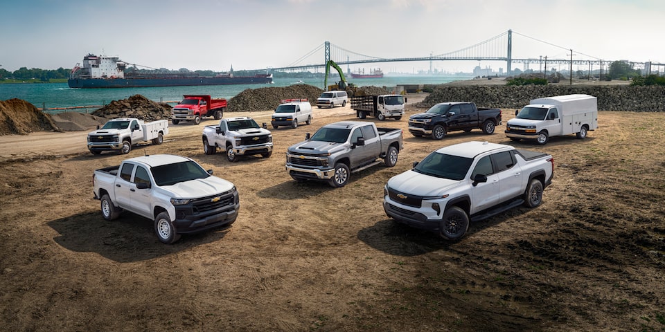 Multiple Chevrolet Silverado work trucks parked outdoors near a construction site.