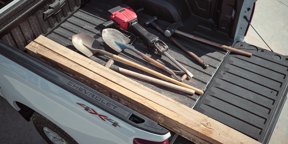 Shovels and other various tools in the bed of a 2025 Chevrolet Silverado LD Work Truck.